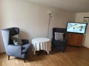 2 Stühle und ein Tisch im Wohnzimmer mit einem TV in der Unterkunft Hotel Andreasstuben in Weißenburg in Bayern
