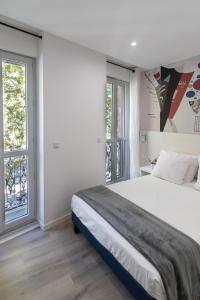 een witte slaapkamer met een groot bed en ramen bij Residence le Pastel Jeanne d'Arc in Toulouse