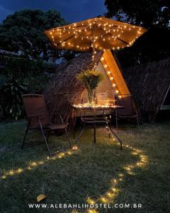 a table and chairs under an umbrella with lights at Smartcamp Ilhabela ᵇʸ ᴬᴸᴱᴮᴬᴴᴸᴵ in Ilhabela