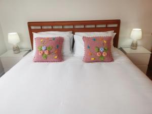 a white bed with two pink pillows and two lamps at Casa do Curral Velho in Santana