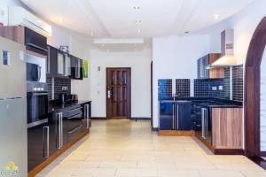 a large kitchen with black appliances and a hallway at Rosy Sea Front Beach Condo in Bamburi