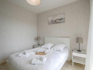 a bedroom with a white bed with towels on it at Le Gréement - Appt vue sur le port in Courseulles-sur-Mer