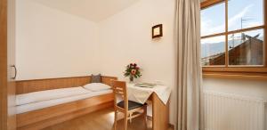 ein kleines Zimmer mit einem Tisch, einem Bett und einem Fenster in der Unterkunft Zieglerhof Appartement 3 in Marling