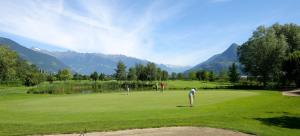 two people playing golf on a lush green course at Zieglerhof Appartement 2 in Marlengo