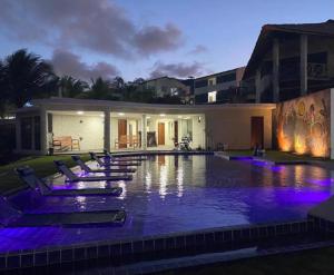a swimming pool at night with purple lights on it at Rota do Mar in Maceió