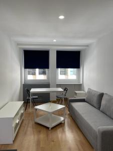 a living room with a couch and a table and two windows at MiniEstudios Plaza de España in Madrid