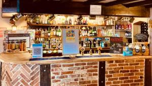 a bar with a brick counter with bottles of alcohol at The George Hotel in Castle Cary