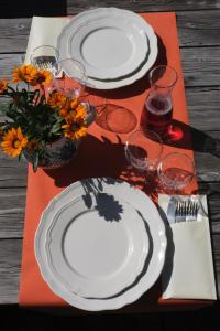 una mesa con platos blancos, vasos y flores. en Hotel Ristoro Vagneur, en Saint Nicolas