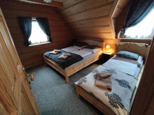 a bedroom with two beds in a wooden cabin at Domki Szwajnosówka in Witów