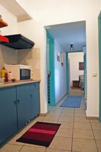 a kitchen with blue cabinets and a microwave and a hallway at Ρήγας: Όμορφα στο Μεσολόγγι, Διαμέρισμα Β2 in Missolonghi