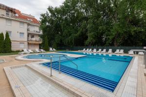 Una gran piscina con sillas y un edificio. en Art Erika Apartment, en Hajdúszoboszló 9 fotos más