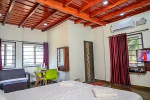 a bedroom with a bed and a tv and a table at Glucklich Beach Cottages in Kundapur