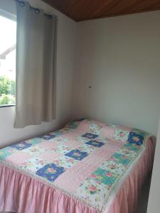 a bed with a quilt on it in a room at Suíte Verde in São Pedro da Aldeia