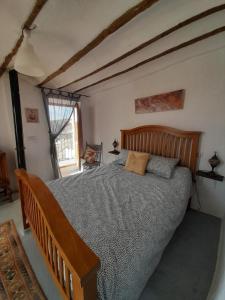 - une chambre avec un grand lit et une tête de lit en bois dans l'établissement Casa De Juanita Vivienda Rural, à Hinojares