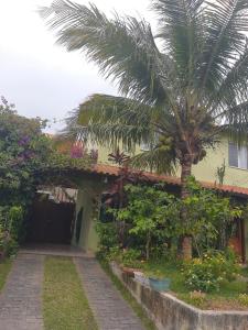 a house with a palm tree in front of it at Suíte Verde in São Pedro da Aldeia