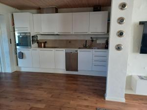 eine Küche mit weißen Schränken und Holzböden in der Unterkunft "City Sleep" in Nykøbing Mors