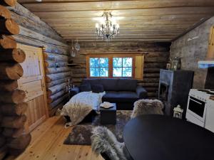 una sala de estar con sofá en una cabaña de madera en Mäntyaho, en Syöte