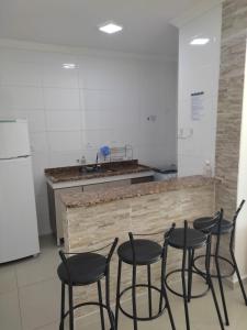 a kitchen with four black chairs in front of a counter at Apartamento Temporada pé na areia in Mongaguá