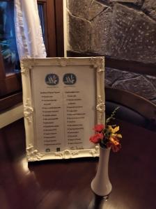 un menu sur une table avec un vase et des fleurs dans l'établissement Hotel Ligeri, à Elati