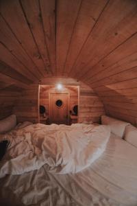 ポスシエにあるDrvena bačva za spavanjeの木製の天井の客室のベッド1台分です。