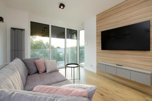 a living room with a couch and a flat screen tv at Apartamenty Perłowa Przystań by Renters in Kołobrzeg