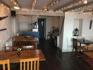 a restaurant with wooden tables and chairs and a kitchen at The Ship Inn in Solva