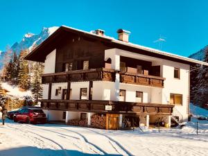 un edificio con un coche rojo estacionado en la nieve en Haus Sonnenspitze - Fam. Nessler, en Biberwier