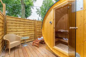 a wooden sauna with a table and a chair on a wooden deck at Natura Ferienpark - Bungalows am Grimnitzsee Schorfheide in Althüttendorf