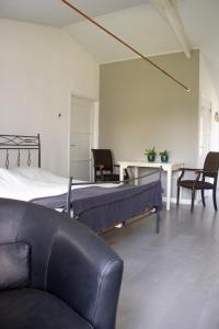 1 dormitorio con cama, sofá y mesa en Huisje en B&B Green Cottage, en Groesbeek