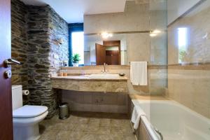 ein Badezimmer mit einem Waschbecken, einer Badewanne und einem WC in der Unterkunft Lar da Mota Boutique Hotel in Arzúa
