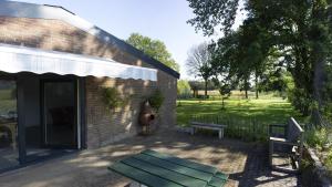 a patio with a bench next to a building at Huisje en B&B Green Cottage in Groesbeek