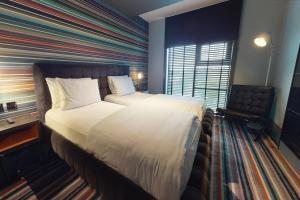 a hotel room with two beds and a large window at Village Hotel London Watford in Elstree