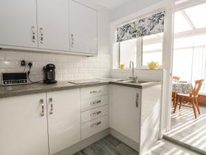 a white kitchen with white cabinets and a window at Sally's Berth in Scarborough