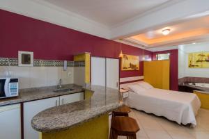 a hotel room with a bed and a kitchen with a counter at Raio do Sol Residence in Bombinhas