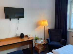 a hotel room with a desk and a chair and a television at Altes Gasthaus Stover in Löningen
