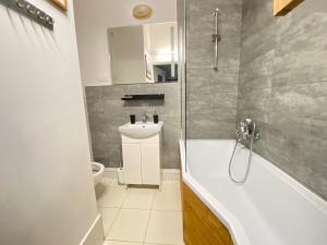 a bathroom with a tub and a toilet and a sink at Kamienica Monte Cassino Sun I 7 min plaża I 2 sypialnie I Balkon in Sopot