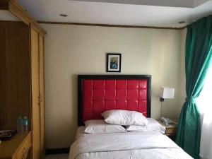 a bed with a red headboard in a bedroom at JR Pension House in Baybay