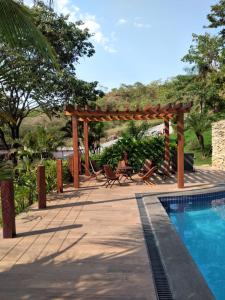a wooden pergola next to a swimming pool at Collina Hotel in Camapuã