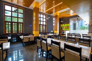 a dining room with tables and chairs and windows at HOTEL VIJAYARANI in Tiruchchirāppalli