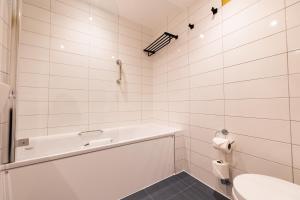 a white bathroom with a tub and a sink at Byron Hotel in London