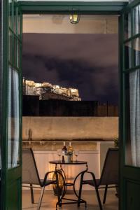 a table on a balcony with a view of a city at Pandrosos Divine Suites in Athens