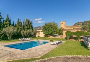 a backyard with a swimming pool with chairs and a building at Historica house with Pool free wifi in Andratx