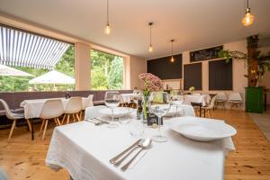 a restaurant with white tables and chairs and windows at Natura Ferienpark - Bungalows am Grimnitzsee Schorfheide in Althüttendorf