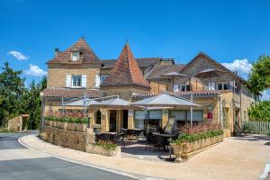 a building with tables and umbrellas in front of it at Hotel Restaurant Laborderie in Tamniès