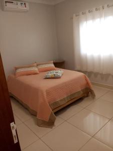 uma cama num quarto branco com uma janela em Casa da Thalita em Pirenópolis