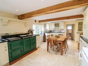 a kitchen with green cabinets and a wooden table at The Farmhouse in Bakewell