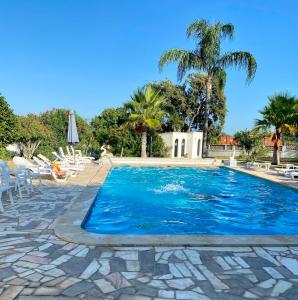 a large swimming pool with chairs and palm trees at Quinta Shiamar in Quarteira