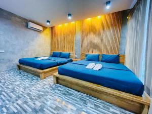 2 łóżka z niebieskimi poduszkami w pokoju w obiekcie SkyHome Wat JD I- Khai Resort & Restaurant w mieście Ban Wat Boek