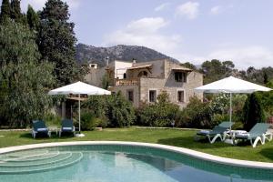 ein Haus mit einem Pool mit Stühlen und Sonnenschirmen in der Unterkunft Hotel Rural Nou Dalt Muntanya in Orient