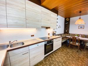 eine Küche mit Holzschränken, einer Spüle und einem Tisch in der Unterkunft Haus Traun-Ufer in Bad Ischl